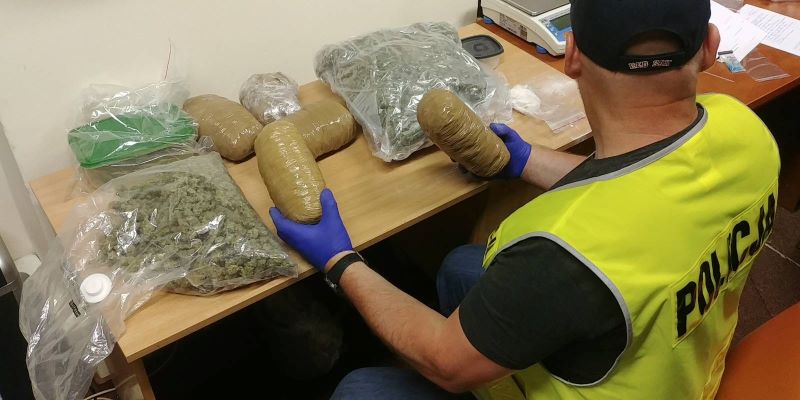 policjant i zarekwirowane narkotyki w foliowych workach