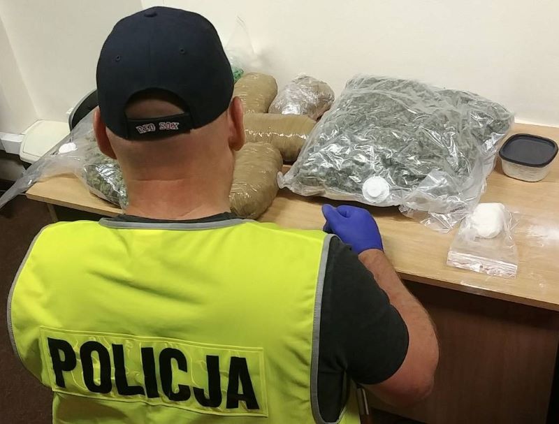 policjant i zarekwirowane narkotyki w foliowych workach