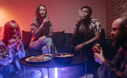 młodzi ludzie na domówce jedzący ciastka z marihuaną, palący zioło i pijący piwo