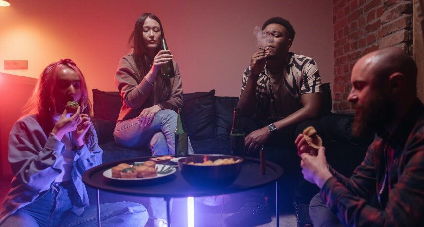 młodzi ludzie na domówce jedzący ciastka z marihuaną, palący zioło i pijący piwo