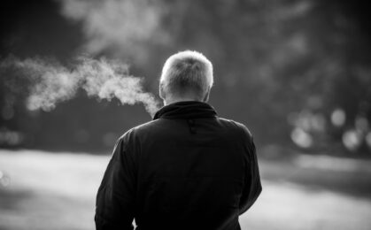 mezczyzna palacy papierossa w parku