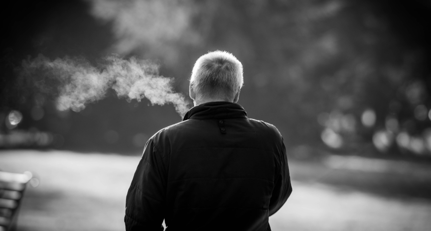 mezczyzna palacy papierossa w parku